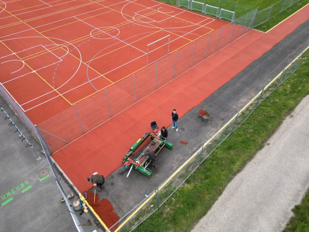 Application du mélange granulat - liant PU, sur la piste d'athlétisme à Marcelin