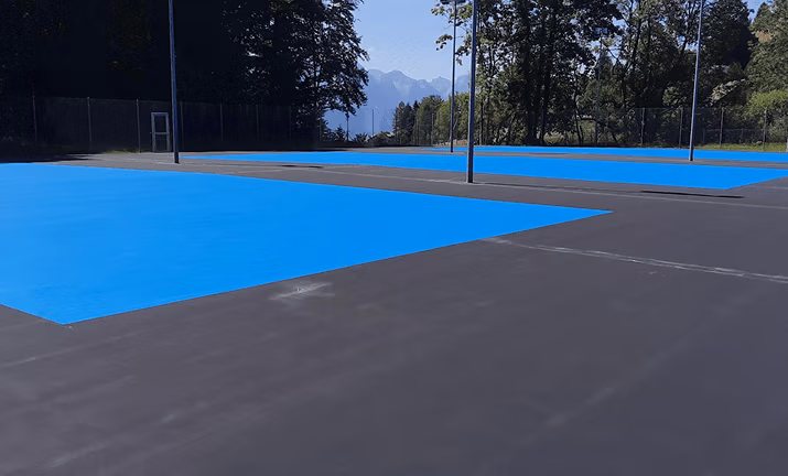 Application des différentes couches de résine sur terrain de tennis.