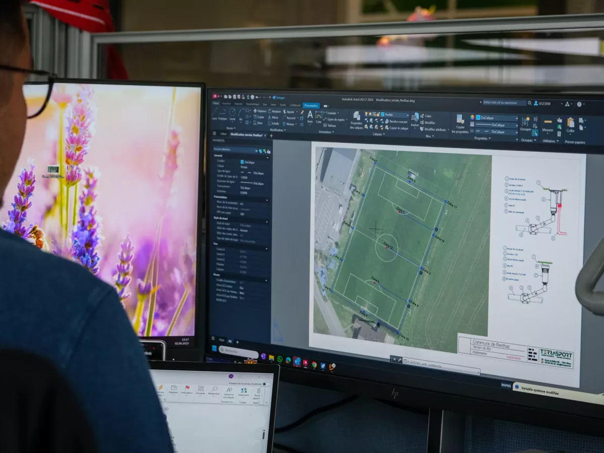 Technicien entrain de dessiner un plan, pour un service d'arrosage automatique sur un terrain de football.