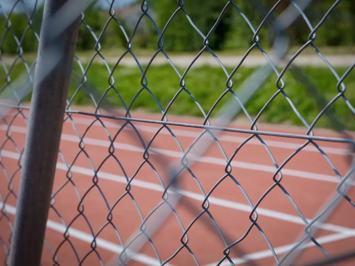 Barrière en grillage autour d'un terrain multisport. Fait partie des équipements sportifs.