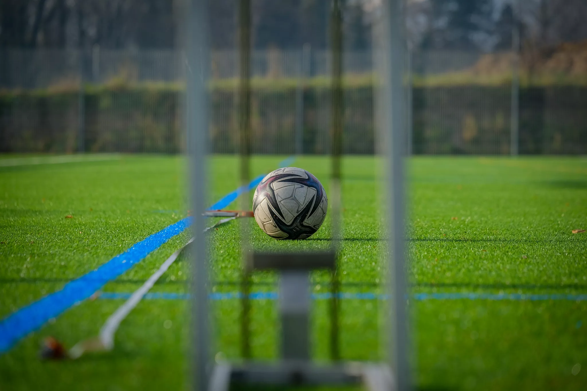 Test du roulement d'un ballon sur un terrain synthétique. L'objectif est que le ballon roule sur plusieurs mètres pour valider la certification.